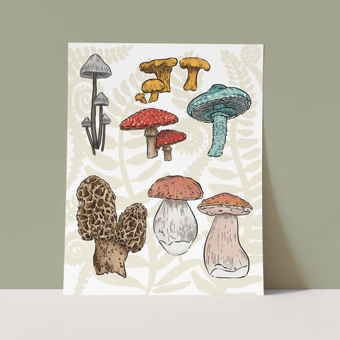 The Mushroom Forest Print features a variety of mushrooms on a pale fern design. The print is propped on a white floor against an earthy green background.